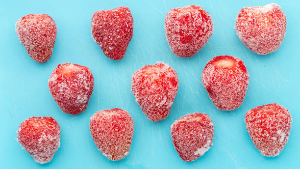 morangos congelados são descongelados em fundo azul. colhendo frutas e frutos para o inverno. close-up de comida congelada. - defreeze - fotografias e filmes do acervo