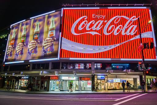 Sydney, Australia - March 9, 2017. The Coca-Cola Billboard in Kings Cross, Sydney, with commercial properties and people, at night.