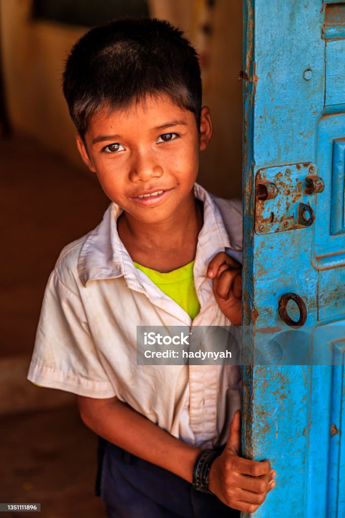 Cambodian schoolboy standing in doorway of school, Cambodia Cambodian schoolboy standing in doorway of school in small village near Tonle Sap, Cambodia. Cambodia Stock Photo