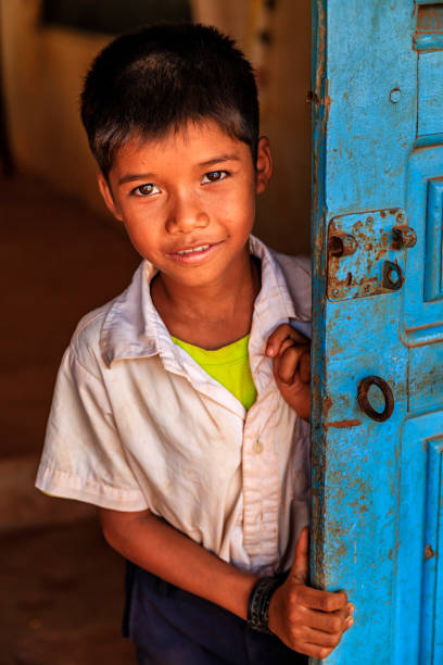 Cambodian schoolboy standing in doorway of school, Cambodia Cambodian schoolboy standing in doorway of school in small village near Tonle Sap, Cambodia. cambodian ethnicity stock pictures, royalty-free photos & images