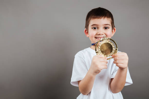 istock Cheerful little boy showing gold trophy medal 1351111949