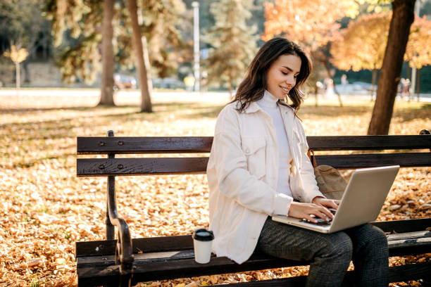 istock Working outdoor sitting on a park bench in fall season 1351112884