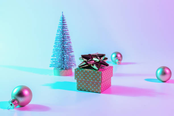istock Christmas composition neon. Holiday decoration bauble ball on neon gradient backdrop. Minimal abstract tree, xmas gift box. New year banner. 1351116174