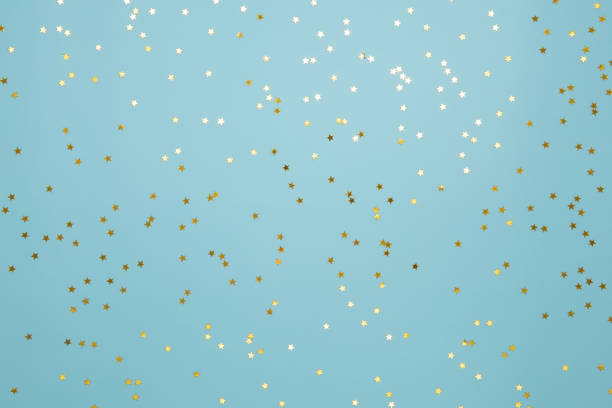 istock Star shaped golden confetti on light blue background 1351119722