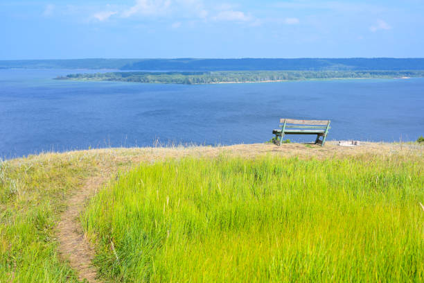 una panchina solitaria su una montagna con una splendida vista sul fiume volga. un luogo per la solitudine, la meditazione, il ripensamento del senso della vita. il luogo più ampio del fiume volga. bellezza paesaggio. - bench mountain park sitting foto e immagini stock