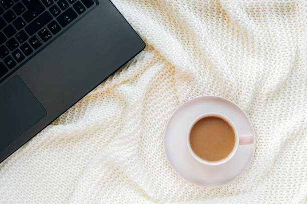 istock A cup of coffee on a white knitted blanket and a notebook computer. Work from home, freelancer concept. Top view, flat lay 1351139287