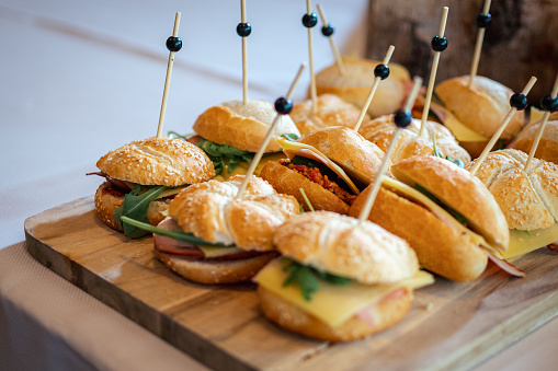 Small sandwiches on a wooden plank. Catering sandwiches with cheese salad and meat