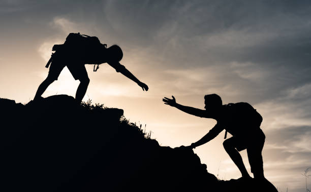 istock Hikers friends helping each other. 1351146219
