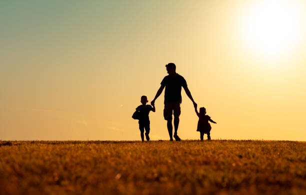 ojciec, syn i córka idą razem o zachodzie słońca. - father fathers day baby child zdjęcia i obrazy z banku zdjęć