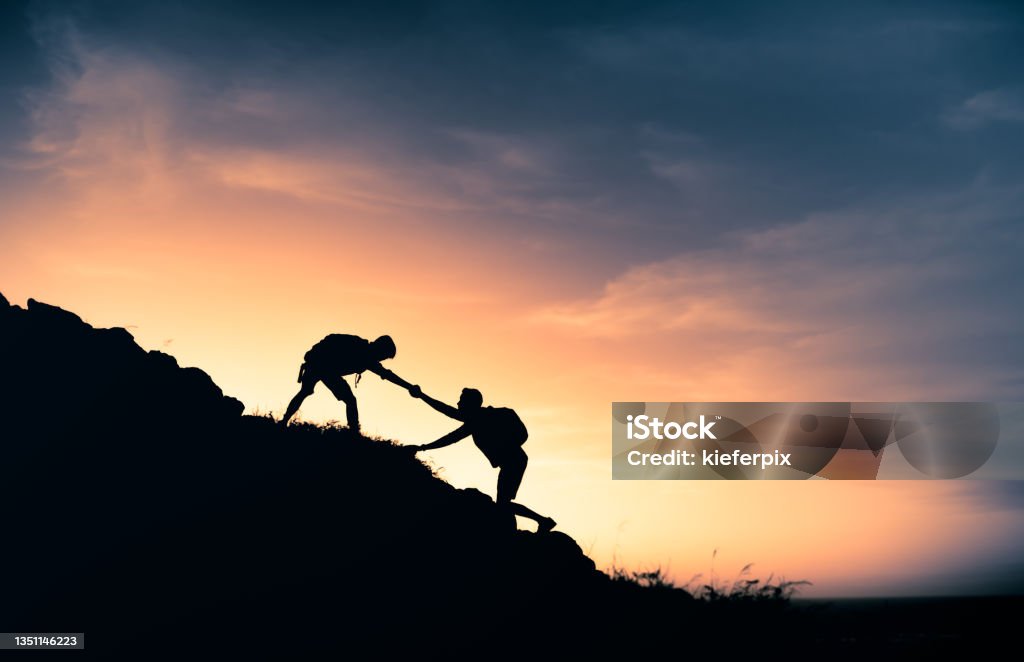 Hikers helping each other Male hikers helping each other on the hike. Mountain Stock Photo