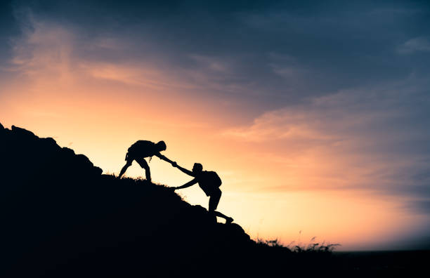 Hikers helping each other stock photo