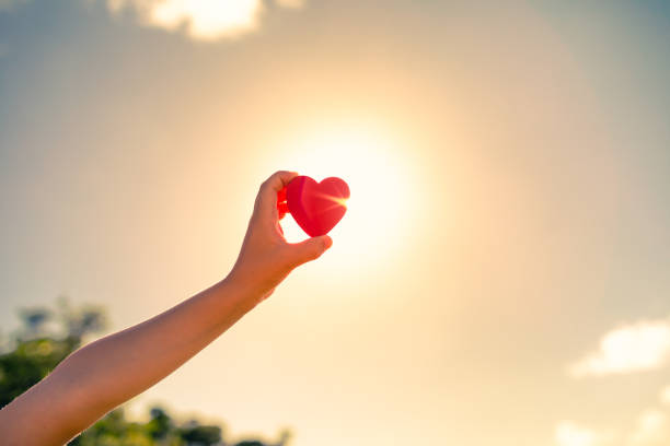 istock Hand holding heart against a sunset sky 1351146257