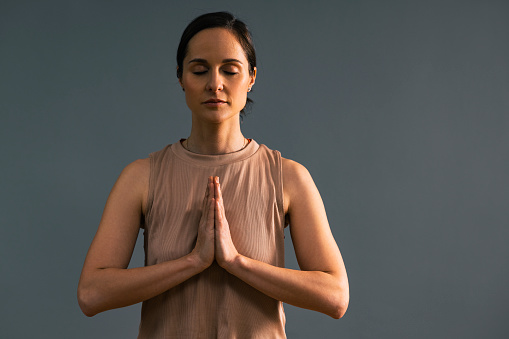 Beautiful woman in sportswear holding hands in namaste gesture