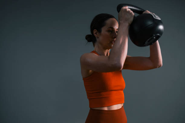istock Woman Exercising with Kettlebell Weights in Gym 1351147729