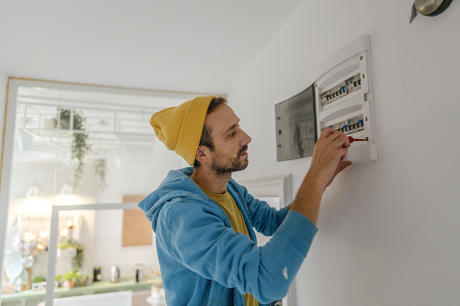 Photo of a young electrician testing a fuse box, making sure everything works properly.