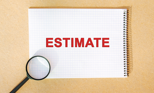 Notebook with the inscription Estimate and a magnifying glass. Process of finding an estimate. Estimation or estimating. Business concept