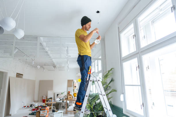 Electrician fixing ceiling lights Photo of a young electrician fixing and changing ceiling lights, using a screwdriver. light fixture stock pictures, royalty-free photos & images