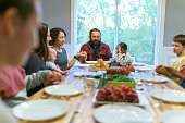 istock Family saying grace at holiday dinner table 1351151087