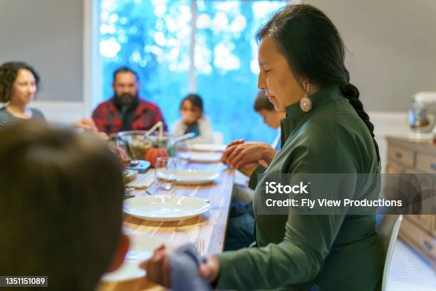 Friends And Family Holding Hands And Praying Before Holiday Dinner Stock Photo - Download Image Now