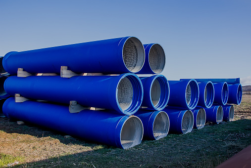 large diameter blue concrete pipes lie in the field. close-up