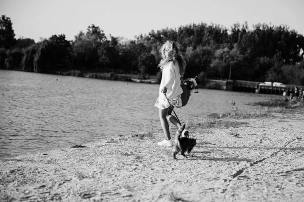 Young blonde, woman, girl running on the beach in spring in a dress and white sweater with a cat on a sunny day