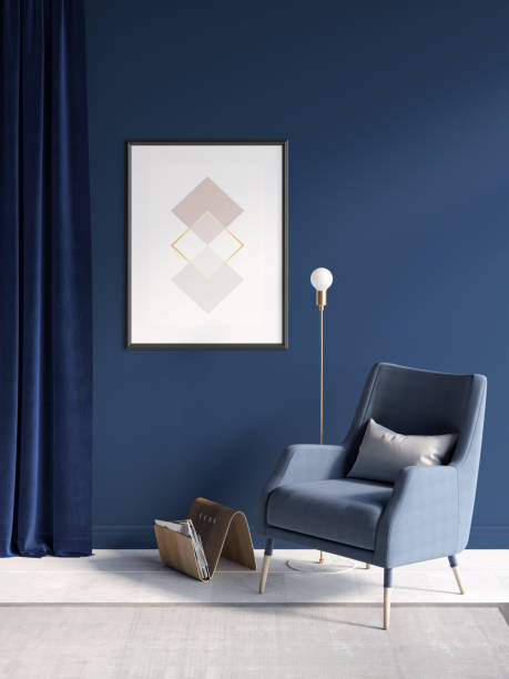 istock Modern room with sunlight on a blue wall, a vertical poster near the deep blue curtains, a wooden magazine rack and a gold lamp near the armchair, a beige carpet on a white parquet floor. 1351156488