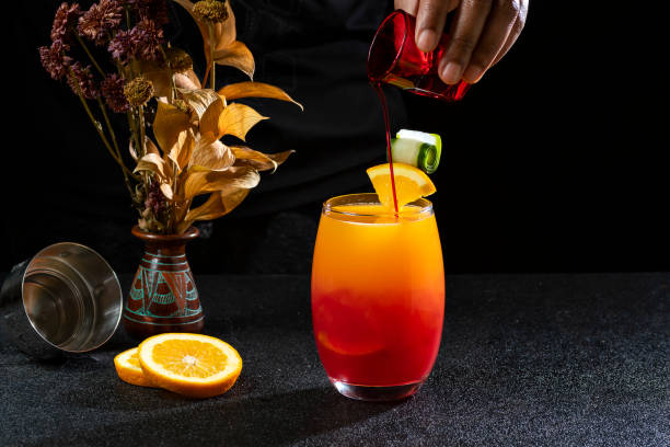 cocktail sesso sulla spiaggia, barman che prepara un cocktail, mettendo grenadine nella bevanda, su sfondo scuro - beach table peach fruit foto e immagini stock