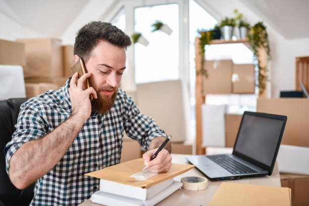istock Bearded Handsome Office Worker Writing Address On Letter While Getting It By Phone 1351162771