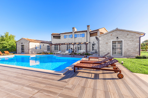 Orland Park, IL, USA - May 20, 2019: A new suburban house with half light brown siding and have brick and stone, brown window shutters, and a front porch.