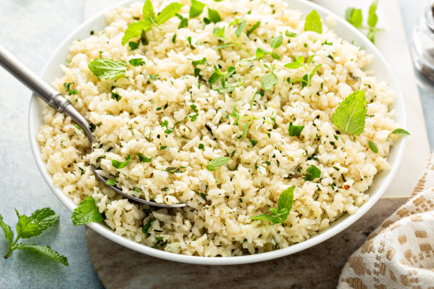 Cauliflower rice with herbs and lemon juice in a white bowl stock photo