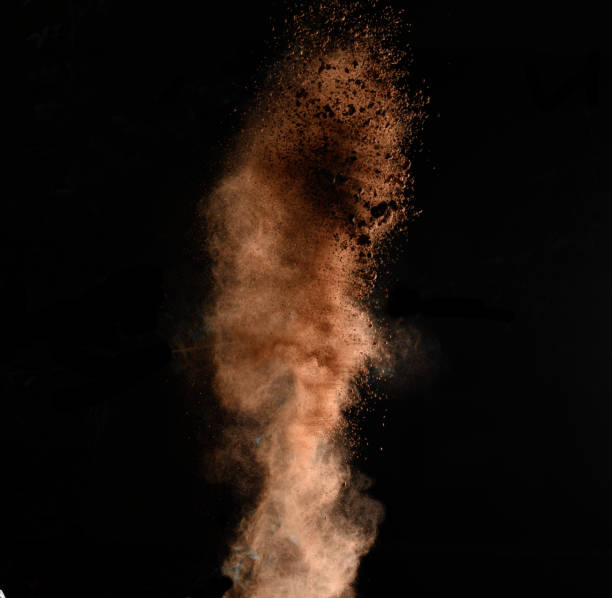 istock flying brown cocoa particles on a black background. Powder flies up 1351170261