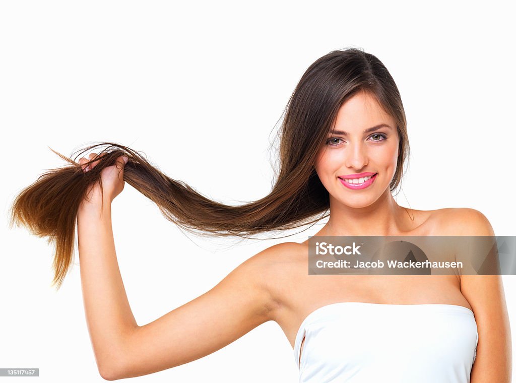 A woman holds her hair against a white background Portrait of a smiling beauty flaunting her healthy hair on a white background Strength Stock Photo