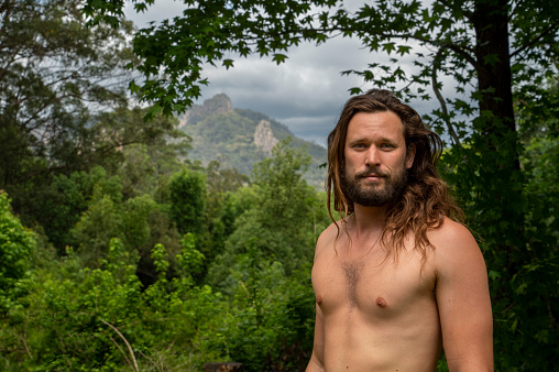 Handsome young alternative lifestyle man standing in front of iconic Nimbin rocks.