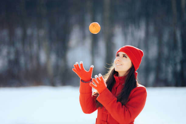 donna che gioca con frutta arancione all'aperto nella stagione invernale - women mature adult smiling cheerful foto e immagini stock