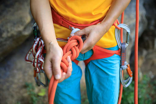 Rock climber belaying while her partner is climbing on the edge of the cliff.