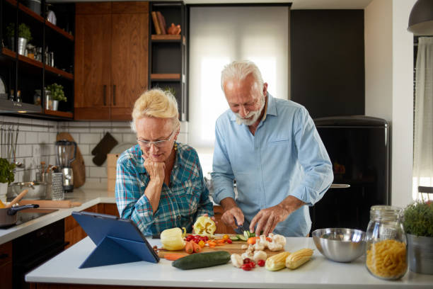 istock Cheerful senior couple preparing healthy meal using online recipe 1351194876