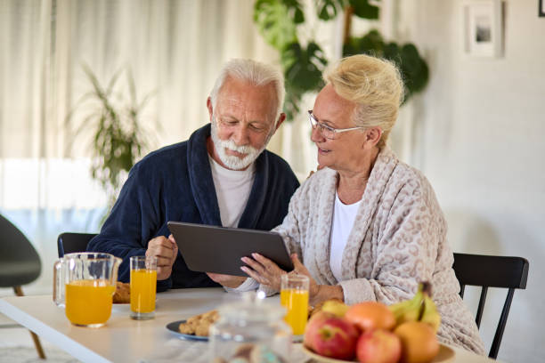 istock Older couple looking at digital tablet over breakfast at home 1351194985