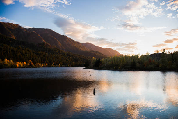 A gorgeous sunset over the mountains in the Columbia River gorge in Oregon. A lake is in the foreground.