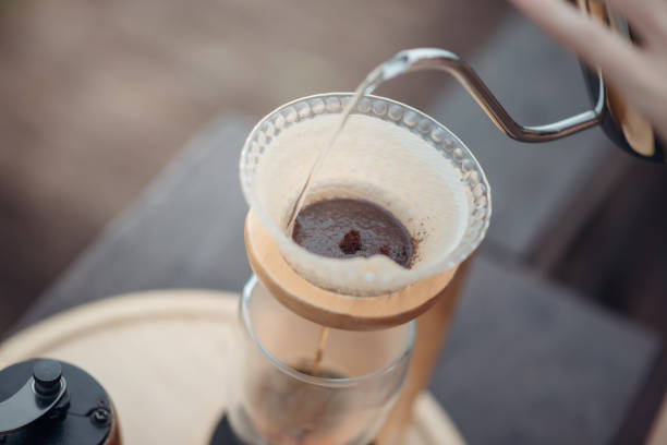 Hand drip coffee, Barista pouring water on the coffee ground with filter. stock photo