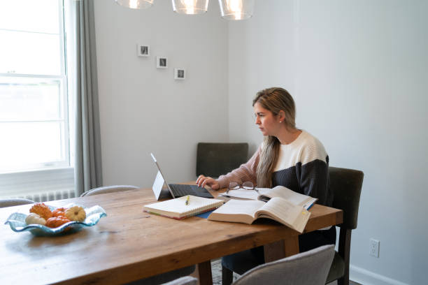 istock Woman studying at home using computer and books 1351198782