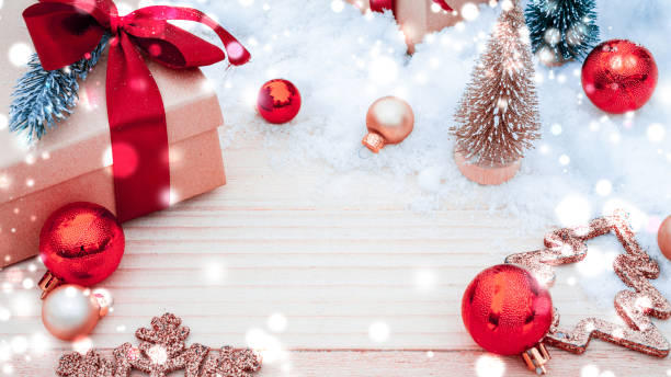 istock Xmas background table. Winter wooden decoration backdrop. Christmas board with old rustic wall, white frozen snow, golden balls and gift box. New year red bow present. 1351202827