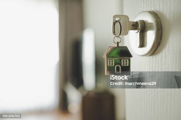 Open The Door And Door Handle With A Key And A Keychain Shaped House Property Investment And House Mortgage Financial Real Estate Concept Stock Photo - Download Image Now