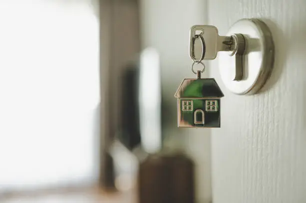 Photo of Open the door and door handle with a key and a keychain shaped house. Property investment and house mortgage financial real estate concept