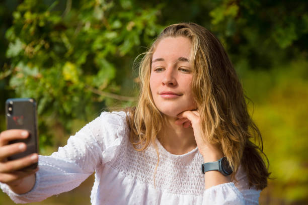 istock beautiful young woman using her smartphone to take photos 1351209801