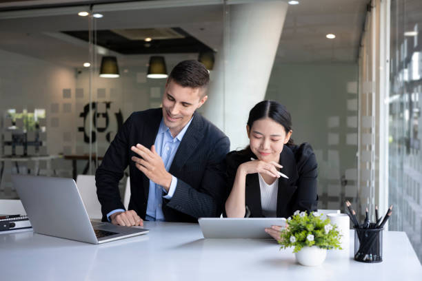 istock Two smiling business colleagues sitting in modern workplace and working together. 1351211886