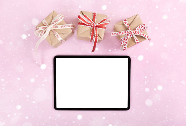 iPad pro with white screen on pink color background with christmas gift. Flatlay.