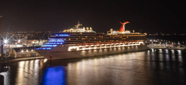Carnival Valor docked in the port of Bridgetown at night. Beautiful reflections on the water in the foreground, port and city lights in the background Bridgetown, Barbados - May 1, 2020: Carnival Valor docked in the port of Bridgetown at night. Beautiful reflections on the water in the foreground, port and city lights in the background. cruise vacation photos stock pictures, royalty-free photos & images
