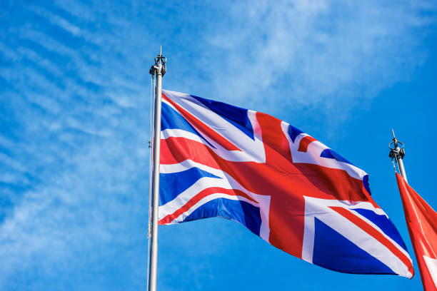 istock UK Flag Blowing in the Wind on Blue Sky with Clouds - Union Jack Flag 1351220228