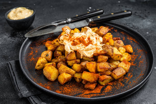 patatas bravas, traditionelle spanische tapas, ofenkartoffeln mit würziger tomatensauce. schwarzer hintergrund. draufsicht - patatas bravas stock-fotos und bilder