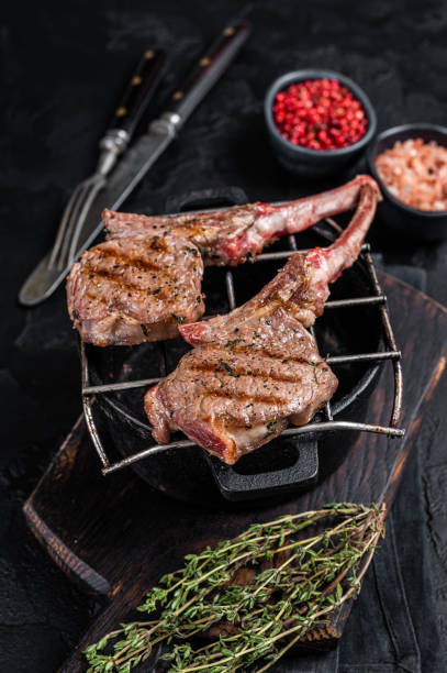 istock Grilled lamb mutton meat chops steaks on a grill. Black background. Top view 1351220748